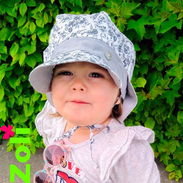 Petite fille souriante portant le chapeau évolutif Zoli en coton fleuri